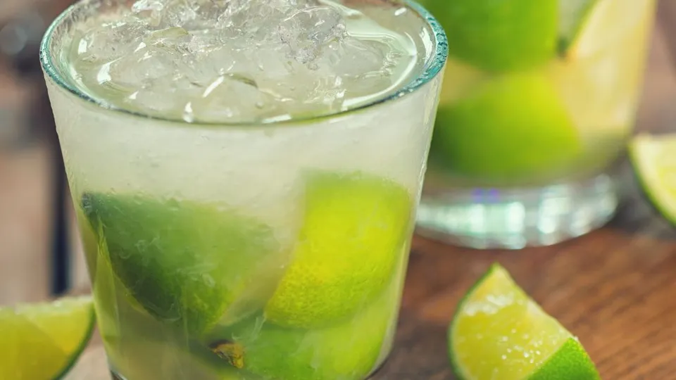 Bicchieri trasparenti con caipirinha, ghiaccio e lime